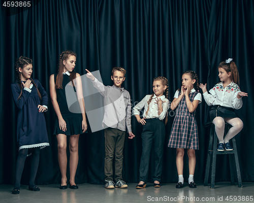 Image of Cute stylish children on dark studio background. The beautiful teen girls and boy standing together