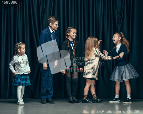 Image of Cute stylish children on dark studio background. The beautiful teen girls and boy standing together