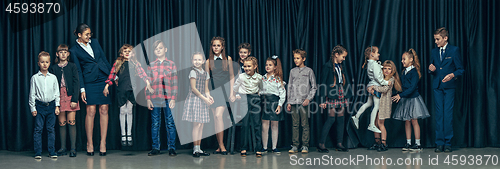 Image of Cute stylish children on dark studio background. The beautiful teen girls and boy standing together
