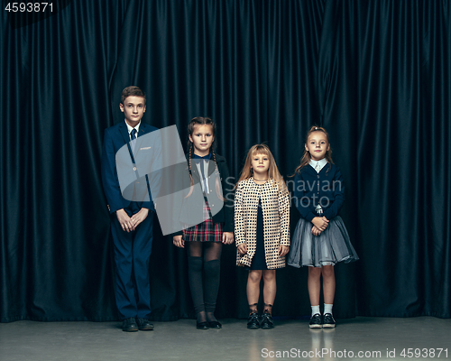 Image of Cute stylish children on dark studio background. The beautiful teen girls and boy standing together