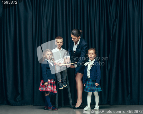 Image of Cute stylish children on dark studio background. The beautiful teen girls and boy standing together