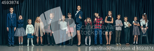 Image of Cute stylish children on dark studio background. The beautiful teen girls and boy standing together
