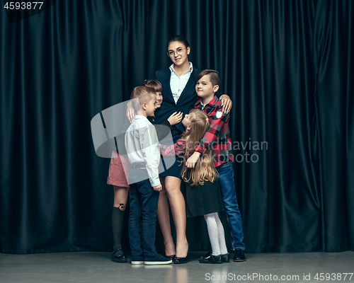 Image of Cute stylish children on dark studio background. The beautiful teen girls and boy standing together