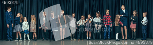 Image of Cute stylish children on dark studio background. The beautiful teen girls and boy standing together