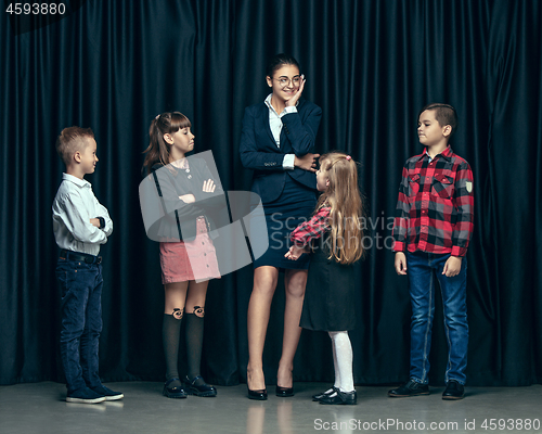 Image of Cute stylish children on dark studio background. The beautiful teen girls and boy standing together