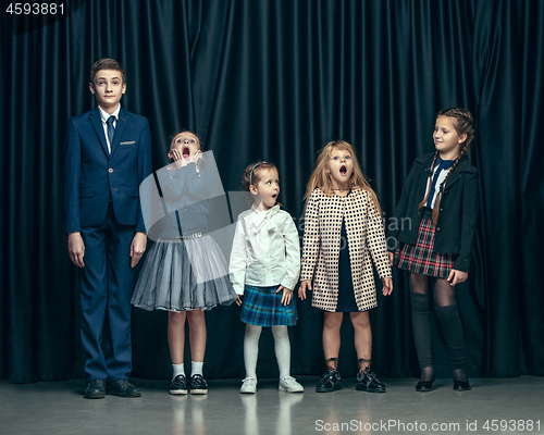 Image of Cute stylish children on dark studio background. The beautiful teen girls and boy standing together