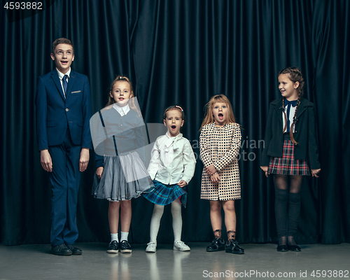 Image of Cute stylish children on dark studio background. The beautiful teen girls and boy standing together