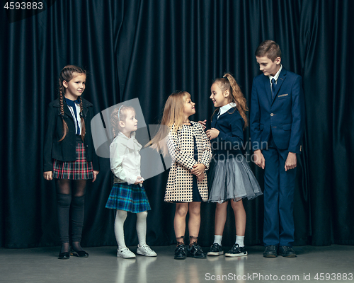 Image of Cute stylish children on dark studio background. The beautiful teen girls and boy standing together