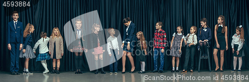 Image of Cute stylish children on dark studio background. The beautiful teen girls and boy standing together