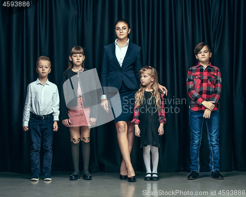 Image of Cute stylish children on dark studio background. The beautiful teen girls and boy standing together