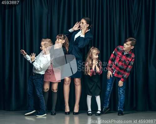 Image of Cute stylish children on dark studio background. The beautiful teen girls and boy standing together