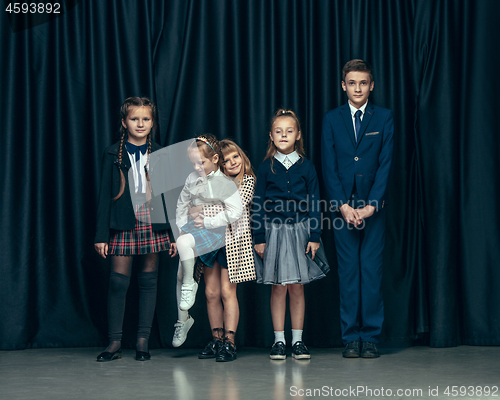 Image of Cute stylish children on dark studio background. The beautiful teen girls and boy standing together