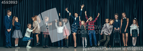 Image of Cute stylish children on dark studio background. The beautiful teen girls and boy standing together