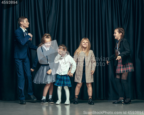 Image of Cute stylish children on dark studio background. The beautiful teen girls and boy standing together