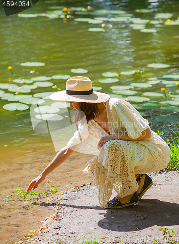 Image of Beautiful woman in a white dress and straw hat on the shore of a