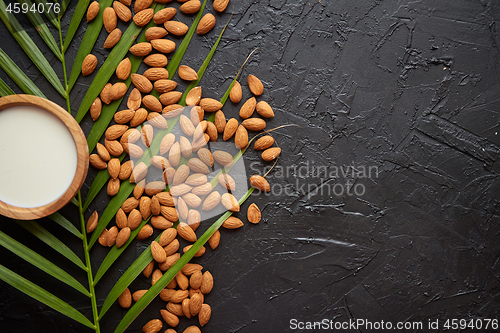 Image of Composition of almonds seeds and milk, placed on black stone background.