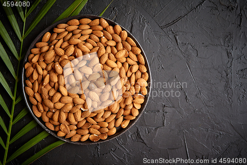 Image of Composition of Whole almond nuts in black plate placed on black stone table