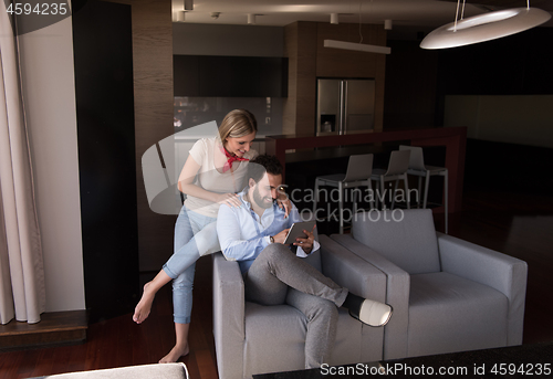 Image of couple relaxing at  home with tablet computers