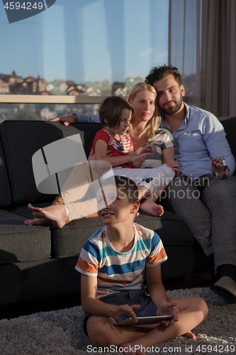 Image of happy young couple spending time with kids at home