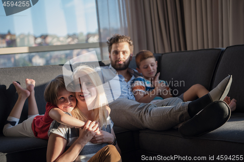 Image of happy young couple spending time with kids at home