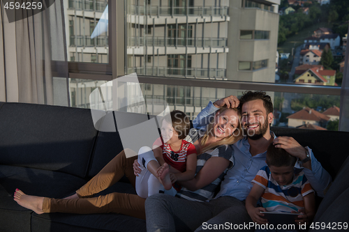 Image of happy young couple spending time with kids at home