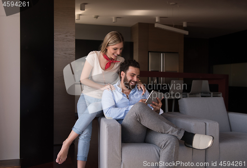 Image of couple relaxing at  home with tablet computers