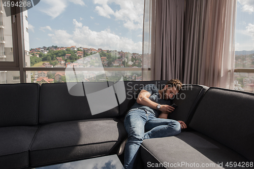 Image of young casual man using a mobile phone at home