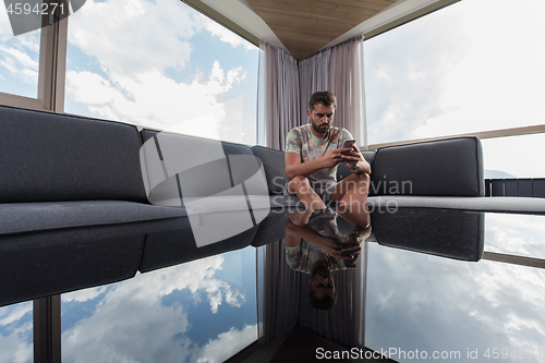 Image of young casual man using a mobile phone at home