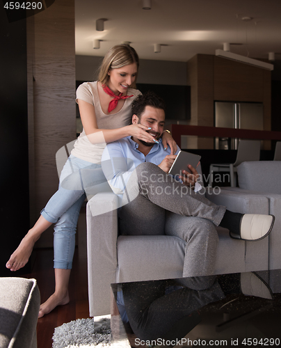 Image of couple relaxing at  home with tablet computers