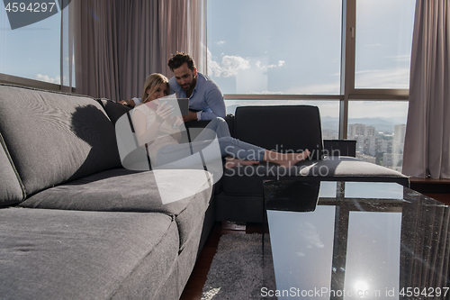 Image of couple relaxing at  home using tablet computer