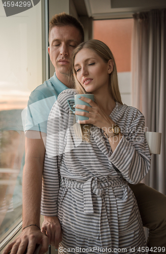 Image of young couple enjoying evening coffee by the window