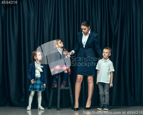 Image of Cute stylish children on dark studio background. The beautiful teen girls and boy standing together