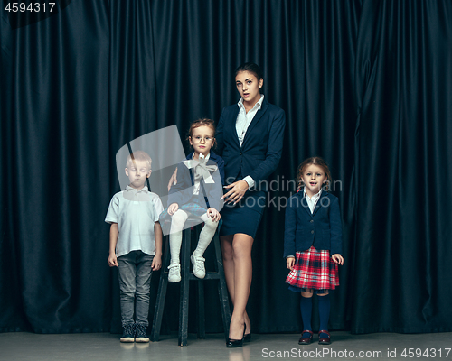 Image of Cute stylish children on dark studio background. The beautiful teen girls and boy standing together