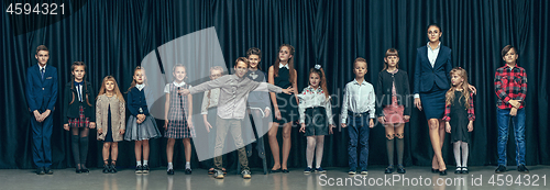 Image of Cute stylish children on dark studio background. The beautiful teen girls and boy standing together