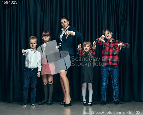 Image of Cute stylish children on dark studio background. The beautiful teen girls and boy standing together