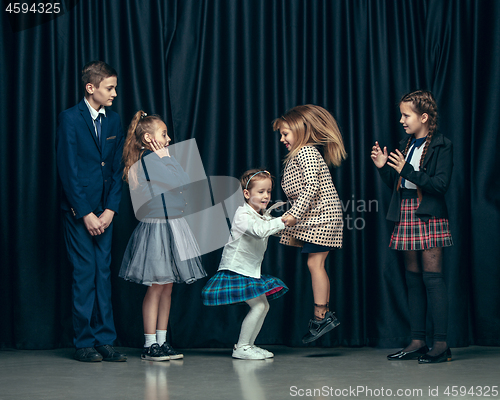 Image of Cute stylish children on dark studio background. The beautiful teen girls and boy standing together