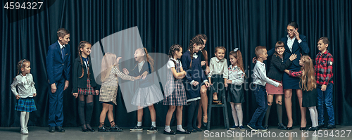 Image of Cute stylish children on dark studio background. The beautiful teen girls and boy standing together