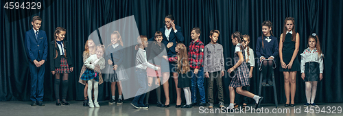 Image of Cute stylish children on dark studio background. The beautiful teen girls and boy standing together