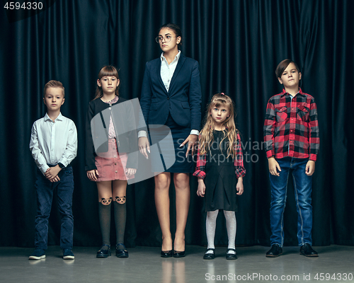 Image of Cute stylish children on dark studio background. The beautiful teen girls and boy standing together