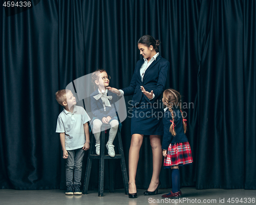 Image of Cute stylish children on dark studio background. The beautiful teen girls and boy standing together