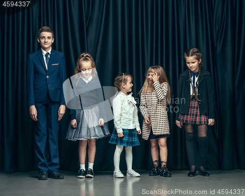 Image of Cute stylish children on dark studio background. The beautiful teen girls and boy standing together