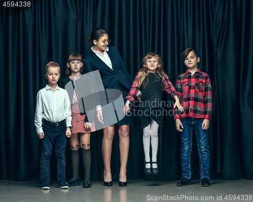 Image of Cute stylish children on dark studio background. The beautiful teen girls and boy standing together