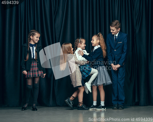 Image of Cute stylish children on dark studio background. The beautiful teen girls and boy standing together