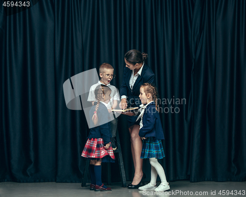 Image of Cute stylish children on dark studio background. The beautiful teen girls and boy standing together