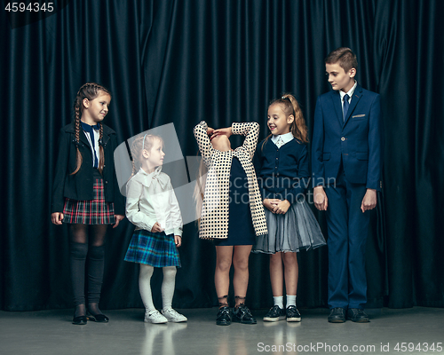 Image of Cute stylish children on dark studio background. The beautiful teen girls and boy standing together