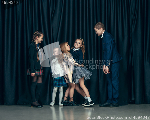 Image of Cute stylish children on dark studio background. The beautiful teen girls and boy standing together