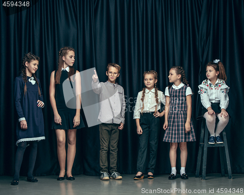 Image of Cute stylish children on dark studio background. The beautiful teen girls and boy standing together