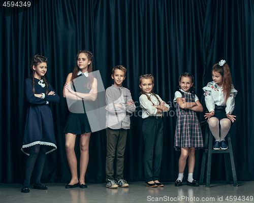 Image of Cute stylish children on dark studio background. The beautiful teen girls and boy standing together