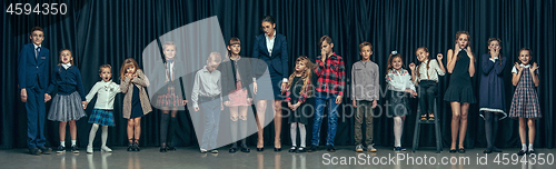 Image of Cute stylish children on dark studio background. The beautiful teen girls and boy standing together