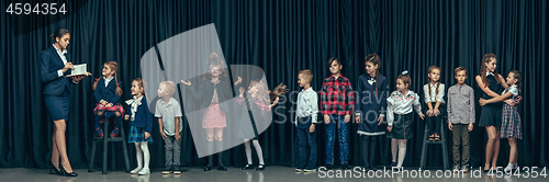 Image of Cute stylish children on dark studio background. The beautiful teen girls and boy standing together